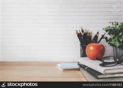 Copyspace of minimal workplace with office supplies on wooden table and white wall background.