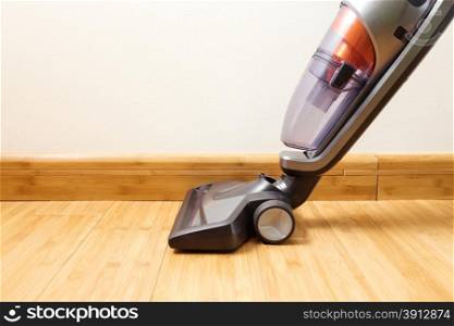 Cordless vertical vacuum cleaner cleaning parquet floor.