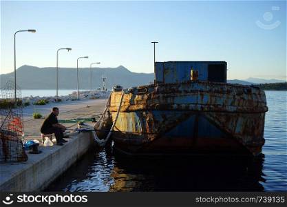 CORFU, GREECE - CIRCA MAY 2019 Fishing near cargo basrge