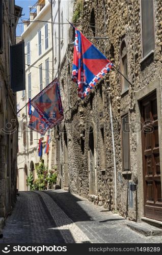 Cori, Latina, Lazio, Italy: typical street of the historic town with red and blue flags
