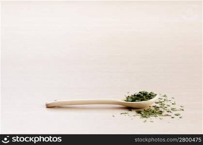 Coriander in a spoon with some spilt over the wooden background