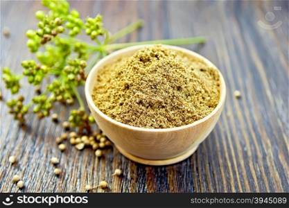 Coriander powder in a bowl, umbrella immature green coriander seeds on the background of wooden boards