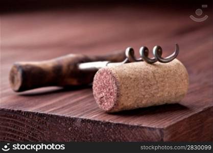 Corkscrew and Cork over wooden background