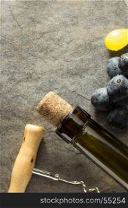 corkscrew and wine bottle with grape on table