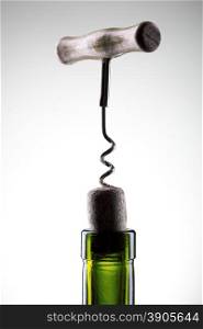 Corkscrew inserted into a wine fuse in a bottle on white
