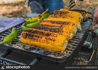 Corn and green chili pepper are cooked on the grill.