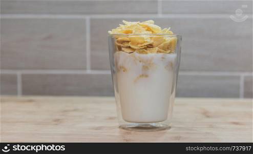 Corn flakes with milk in glass cup.. Corn flakes with milk in glass cup