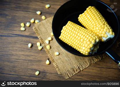 Corn on pot pan for cooking sweet corn ears on wooden background , close up