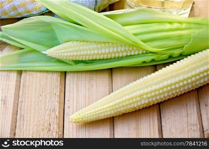 Corn on the cob, napkin oil in a bottle on the background of wooden boards
