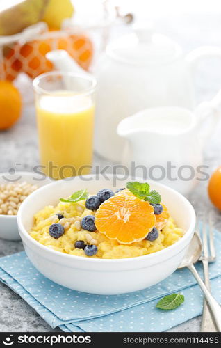 Corn porridge with fresh blueberry, orange and pine nuts in bowl served for breakfast