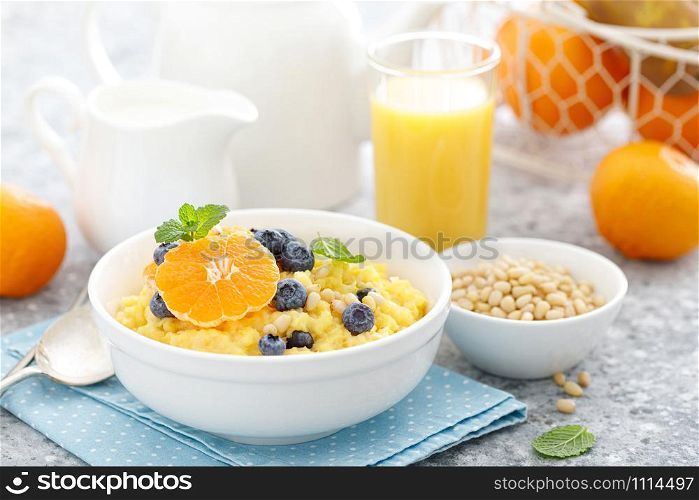 Corn porridge with fresh blueberry, orange and pine nuts in bowl served for breakfast