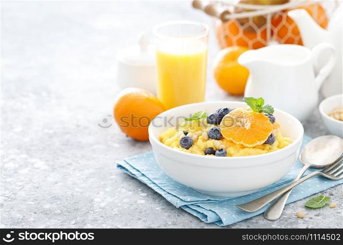 Corn porridge with fresh blueberry, orange and pine nuts in bowl served for breakfast