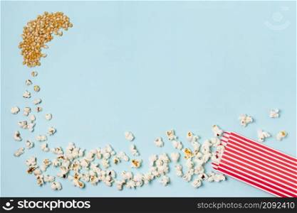 corn seeds turns into popcorns enter popcorn box against blue backdrop