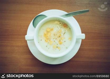 Corn soup in white cup on a table isolated