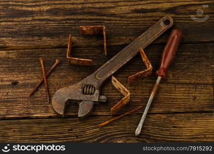 corner braces, screws, screwdriver and adjustable wrench on wooden background