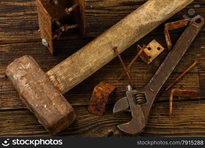 corner braces, screws, screwdriver, sledge hammer and adjustable wrench on wooden background