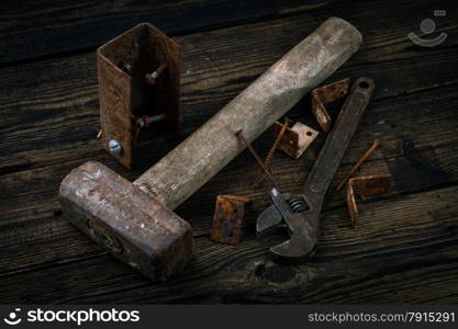 corner braces, screws, screwdriver, sledge hammer and adjustable wrench on wooden background
