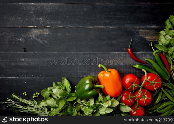 Corner frame of fresh vegetables and herbs on a wooden background with space under the text. Cherry tomatoes, basil, pepper, green peas and rosemary on a wooden background, flat lay. Ingredients vegetables and herbs for a fresh salad on a wooden background lined with a frame
