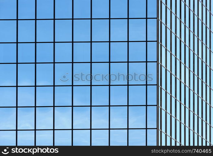 Corner of office building windows in square grid pattern reflecting sky.