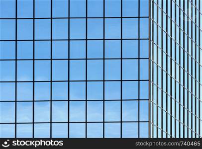 Corner of office building windows in square grid pattern reflecting sky.
