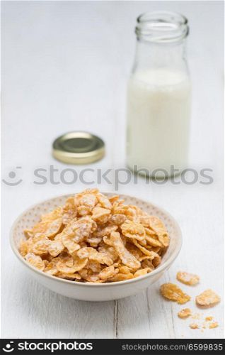 Cornflakes in a bowl and milk bottle.. Cornflakes in a bowl and milk bottle
