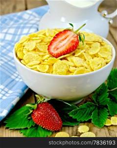 Cornflakes in a white bowl, leaves and strawberries, milk in a jug, a napkin on the background of wooden boards