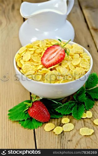 Cornflakes in a white bowl, leaves and strawberries, milk in a jug on a wooden boards background