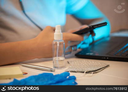 Coronavirus concept. Woman working in office. Sanitizer spray and protective gloves on the foreground. working in new reality