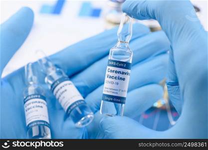 Coronavirus COVID-19 small single dose vaccine vial in scientist hands concept. Research for new novel corona virus immunization drug.