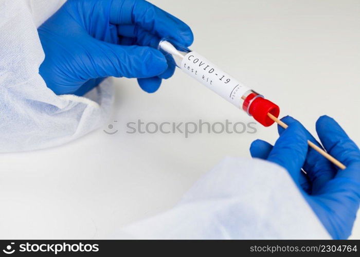 Coronavirus COVID-19 testing kit,swab collection equipment,sterile vacutainer with swabbing stick,closeup of hands in blue protective gloves holding the test tube,rt-PCR s&le specimen testing