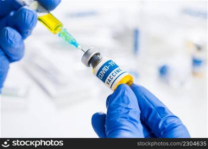 Coronavirus COVID-19 vaccine development,research for cure and treatment of infected patients,groundbreaking discovery in battle against SARS-CoV-2 pathogen,hands in gloves holding&oule and syringe