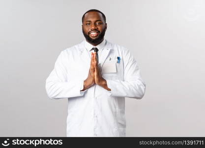 Coronavirus, covid19 and healthcare concept. Handsome happy african-american bearded doctor in white coat, press hands in pray, thankful namaste sign, asking for help or thanking.. Coronavirus, covid19 and healthcare concept. Handsome happy african-american bearded doctor in white coat, press hands in pray, thankful namaste sign, asking for help or thanking