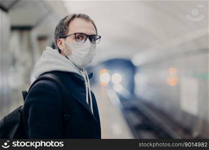 Coronavirus crisis. Male follows quarantine rules wears protective medical mask, travels in public transport cares about health during epidemic or pandemic. Danger of catching virus in city transport