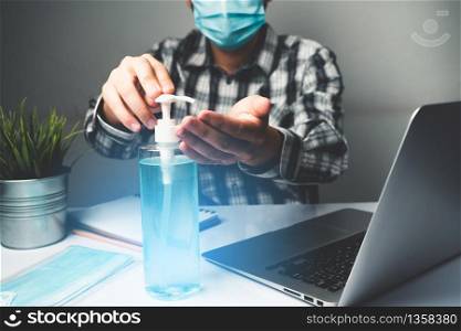 Coronavirus disease or COVID-19 protection concept - Young man work in office room at home with protective and cleaning equipment to protect against corona virus while using laptop computer at desk.
