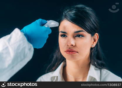 Coronavirus. Medical worker in hazmat protective suite checking body temperature, woman with protective mask