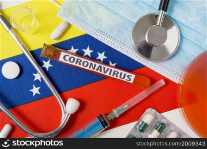 Coronavirus, nCoV concept. A protective breathing mask, a stethoscope, a syringe, and tablets on the flag of Venezuela are visible from above . A new outbreak of the Chinese coronavirus. Coronavirus, nCoV concept. A protective breathing mask, a stethoscope, a syringe, and tablets on the flag of Venezuela are visible from above .