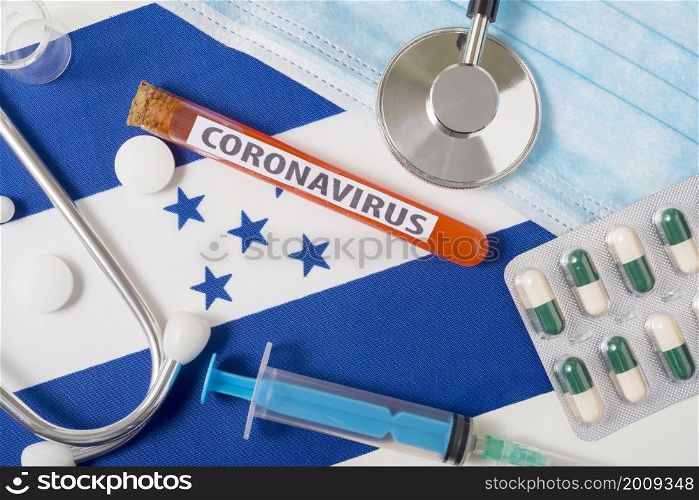 Coronavirus, nCoV concept. A protective breathing mask, stethoscope, syringe, and pills on the flag of Honduras are visible from above. A new outbreak of the Chinese coronavirus. Coronavirus, nCoV concept. A protective breathing mask, stethoscope, syringe, and pills on the flag of Honduras are visible from above.