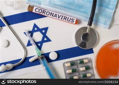 Coronavirus, nCoV concept. Top view of a protective breathing mask, stethoscope, syringe, pills on the flag of Israel. A new outbreak of the Chinese coronavirus. Coronavirus, nCoV concept. Top view of a protective breathing mask, stethoscope, syringe, pills on the flag of Israel.