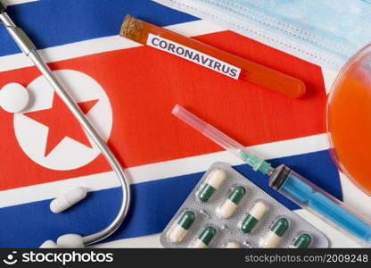 Coronavirus, nCoV concept. Top view of a protective breathing mask, stethoscope, syringe, pills on the flag of North Korea, North Korea. A new outbreak of the Chinese coronavirus. Coronavirus, nCoV concept. Top view of a protective breathing mask, stethoscope, syringe, pills on the flag of North Korea, North Korea.