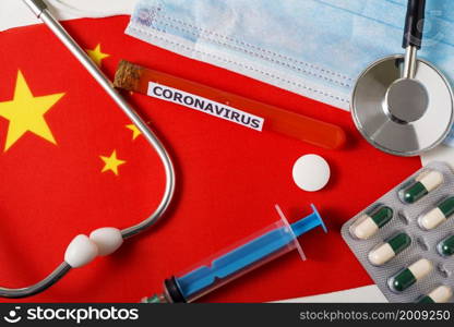 Coronavirus, nCoV concept. Top view of a protective breathing mask, stethoscope, syringe, pills on the flag of China. A new outbreak of the Chinese coronavirus. Coronavirus, nCoV concept. Top view of a protective breathing mask, stethoscope, syringe, pills on the flag of China.