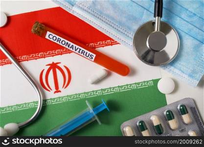 Coronavirus, nCoV concept. Top view of a protective breathing mask, stethoscope, syringe, pills on the flag of Iran. A new outbreak of the Chinese coronavirus. Coronavirus, nCoV concept. Top view of a protective breathing mask, stethoscope, syringe, pills on the flag of Iran.