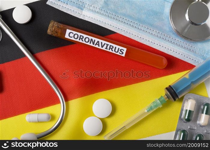 Coronavirus, nCoV concept. Top view protective breathing mask, stethoscope, syringe, pills on the flag of Germany. A new outbreak of the Chinese coronavirus. Coronavirus, nCoV concept. Top view protective breathing mask, stethoscope, syringe, pills on the flag of Germany.