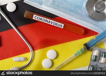 Coronavirus, nCoV concept. Top view protective breathing mask, stethoscope, syringe, pills on the flag of Germany. A new outbreak of the Chinese coronavirus. Coronavirus, nCoV concept. Top view protective breathing mask, stethoscope, syringe, pills on the flag of Germany.