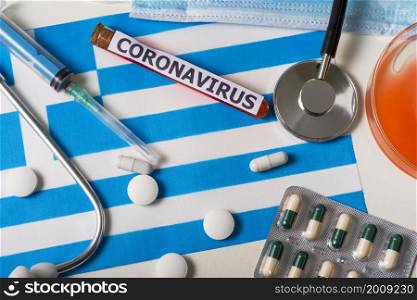 Coronavirus, nCoV concept. Top view protective breathing mask, stethoscope, syringe, pills on the flag of Greece. A new outbreak of the Chinese coronavirus. Coronavirus, nCoV concept. Top view protective breathing mask, stethoscope, syringe, pills on the flag of Greece.