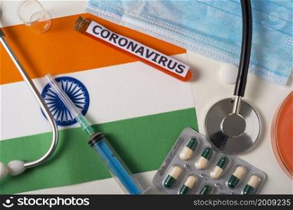 Coronavirus, nCoV concept. Top view protective breathing mask, stethoscope, syringe, pills on the flag of India. A new outbreak of the Chinese coronavirus. Coronavirus, nCoV concept. Top view protective breathing mask, stethoscope, syringe, pills on the flag of India.