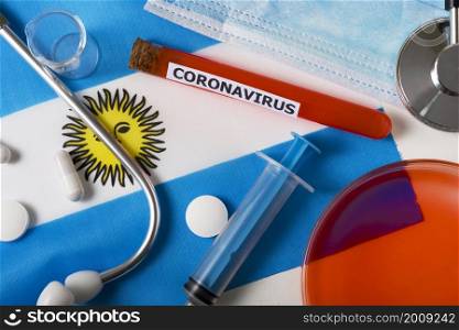 Coronavirus, nCoV concept. Top view protective breathing mask, stethoscope, syringe, pills on the flag of Argentina. A new outbreak of the Chinese coronavirus. Coronavirus, nCoV concept. Top view protective breathing mask, stethoscope, syringe, pills on the flag of Argentina.