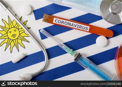 Coronavirus, nCoV concept. Top view protective breathing mask, stethoscope, syringe, pills on the flag of Uruguay. A new outbreak of the Chinese coronavirus. Coronavirus, nCoV concept. Top view protective breathing mask, stethoscope, syringe, pills on the flag of Uruguay.