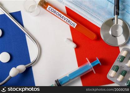 Coronavirus, nCoV concept. Top view protective breathing mask, stethoscope, syringe, pills on the flag of France. A new outbreak of the Chinese coronavirus. Coronavirus, nCoV concept. Top view protective breathing mask, stethoscope, syringe, pills on the flag of France.