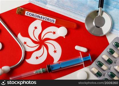 Coronavirus, nCoV concept. Top view protective breathing mask, stethoscope, syringe, pills on the Hong Kong flag . A new outbreak of the Chinese coronavirus. Coronavirus, nCoV concept. Top view protective breathing mask, stethoscope, syringe, pills on the Hong Kong flag .
