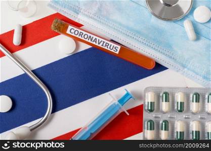 Coronavirus, nCoV concept. Top view protective breathing mask, stethoscope, syringe, pills on the flag of Thailand. A new outbreak of the Chinese coronavirus. Coronavirus, nCoV concept. Top view protective breathing mask, stethoscope, syringe, pills on the flag of Thailand.